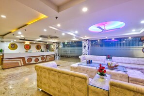 A hotel lobby with a reception desk, sofas, a ceiling fan, and a glass wall. - Hotel All Time Residency New Delhi (New Delhi)