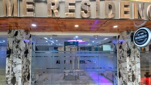 L’entrée d’un hôtel, avec une façade en marbre, une porte en verre et une enseigne indiquant « ALL TIME RESIDENCY NEW DELHI ».