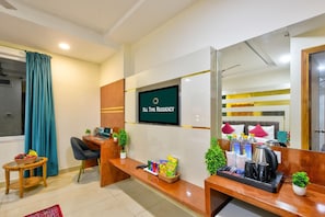 A reception desk with a TV screen displaying 'All Time Residency,' a desk with a laptop, a basket of snacks, and a coffee maker. - Hotel All Time Residency New Delhi (New Delhi)