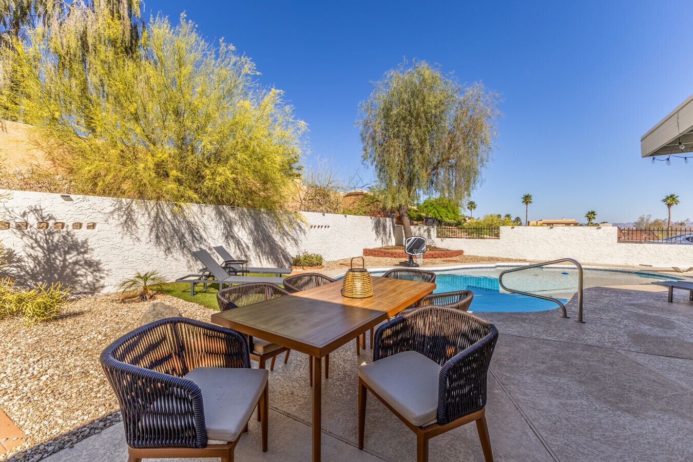 Une terrasse extérieure avec une piscine, des meubles en osier et une vue sur le paysage environnant.