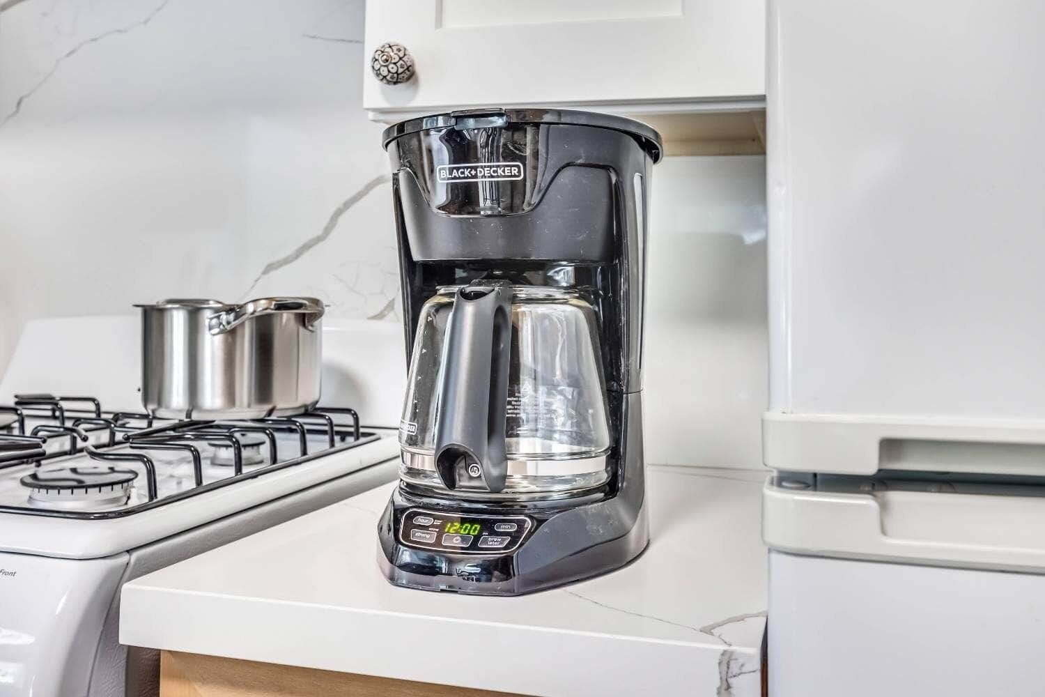 Et køkken med kaffemaskine, komfur og gryde på bordet.
