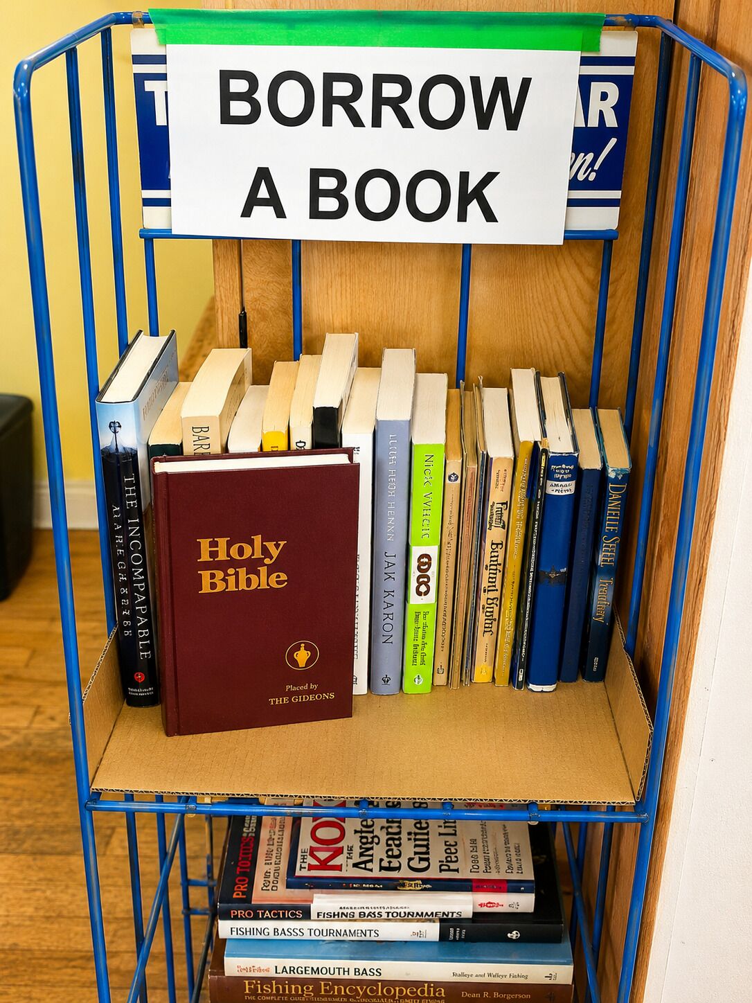 A book cart with a sign that says 'BORROW A BOOK' and various books including a Holy Bible.