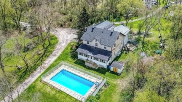 Une grande maison avec une piscine, entourée d’arbres et d’une pelouse bien entretenue.
