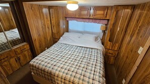 Une chambre à coucher avec un lit, des murs en bois, une fenêtre avec des stores et un miroir.