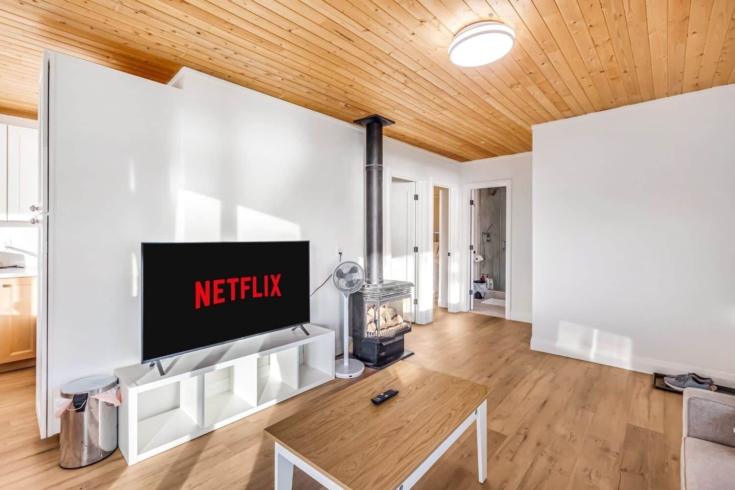 A modern living room with a flat-screen TV, a wood-burning stove, and a minimalist design.