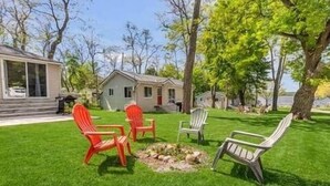 A grassy outdoor area with outdoor seating and a small fire pit.