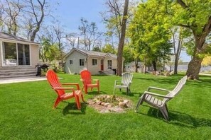 A grassy outdoor area with outdoor seating and a small fire pit.