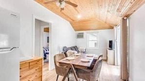 A compact kitchen with a refrigerator, wooden cabinets, and a dining area with a table and chairs.