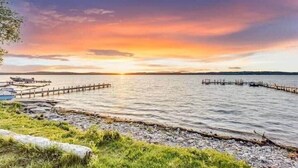 A lakeside view with a wooden pier extending into the water, surrounded by grassy areas.