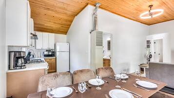 A modern kitchen with white cabinets, a stainless steel coffee maker, and a built-in microwave.