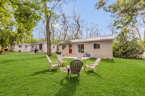 A single-story house with a red door, a front porch with four chairs, and a lawn. - #3 Cottage - Morocco (Hamilton)