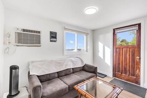Un salon avec un canapé, une table basse en verre, une porte et une fenêtre.
