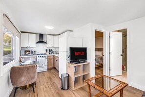 Un espace de vie compact comprenant un coin cuisine, un coin repas, un téléviseur et une chambre.