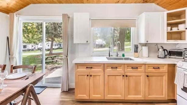 A kitchen with wooden cabinets, a sink, and a window overlooking a grassy area.