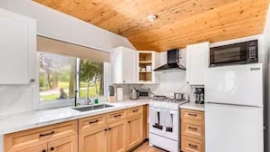 A modern kitchen with wooden cabinets, a white countertop, a stove, and a refrigerator.