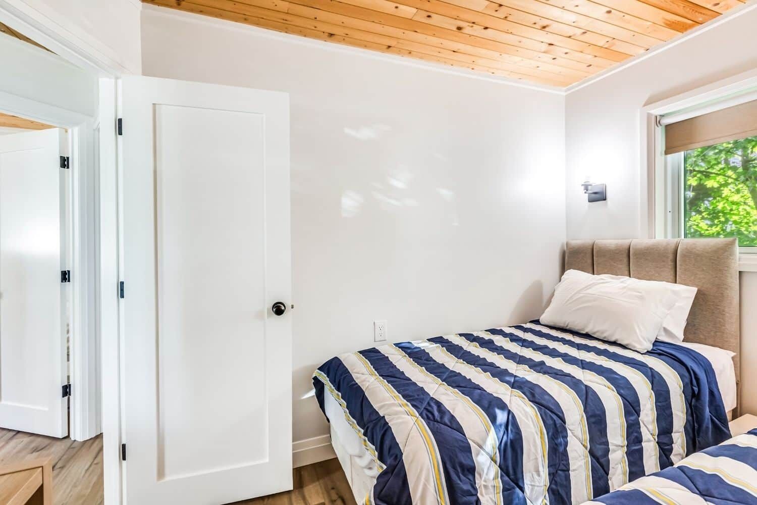 Une chambre à coucher avec un lit, une table de chevet, une fenêtre donnant sur un beau paysage et une porte.
