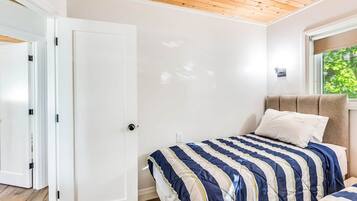 Une chambre à coucher avec un lit, une table de chevet, une fenêtre donnant sur un beau paysage et une porte.