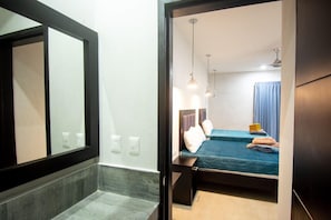 Una habitación de hotel con una cama, mesitas de noche y un espejo.