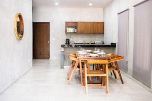 Una cocina moderna con armarios de madera, una mesa de comedor para cuatro personas y un espejo grande en la pared.