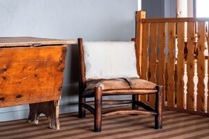 Une chaise en bois dotée d’un siège et d’un dossier rembourrés, placée à côté d’un bureau en bois et d’une barrière en bois.