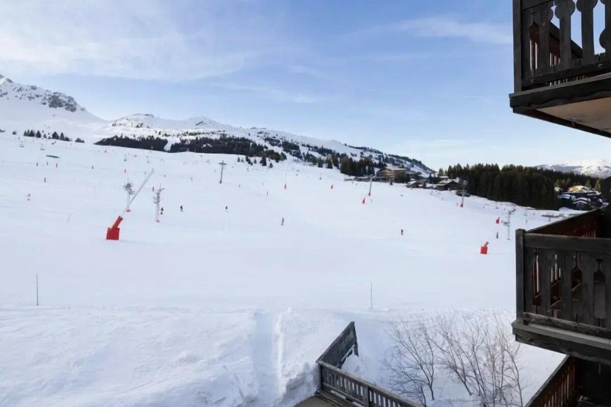 A snowy ski slope with ski lifts and a wooden building with a balcony.