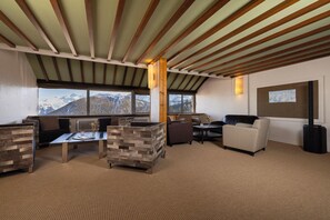 A modern interior with a high ceiling, large windows offering mountain views, and a mix of seating arrangements including sofas and chairs. - Crystal Hôtel Courchevel (Les Allues)