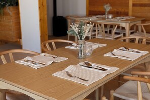 A dining table with a vase of dried flowers, neatly set with cutlery and placemats. - Crystal Hôtel Courchevel (Les Allues)
