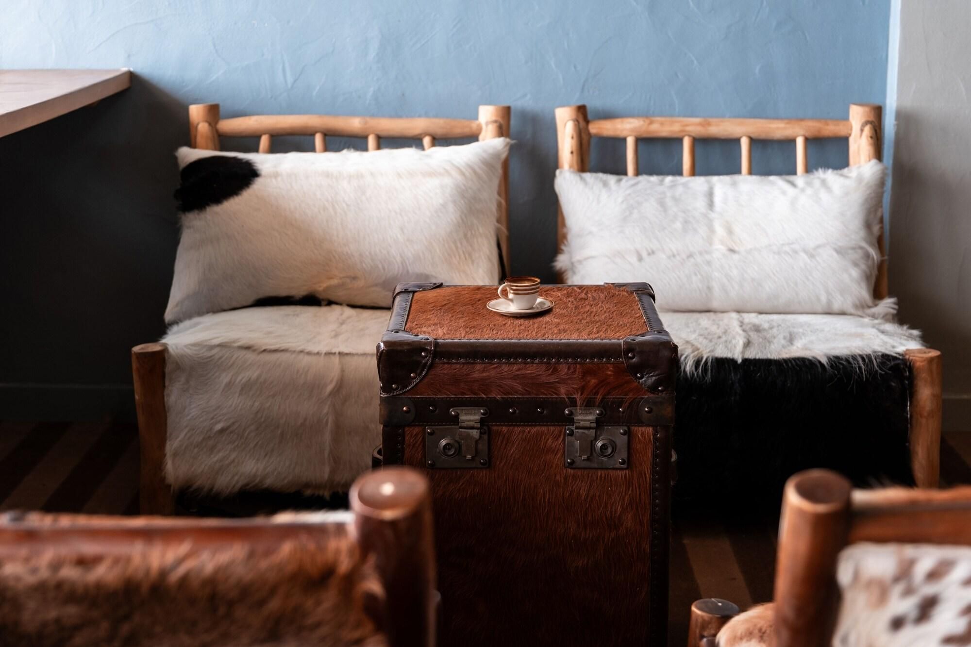 A cozy room with a wooden bed, a fur-covered chair, and a vintage suitcase.