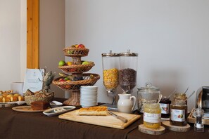 A breakfast buffet with wicker fruit baskets, cereal dispensers, and various spreads. - Crystal Hôtel Courchevel (Les Allues)