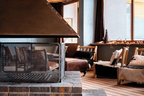 A fireplace with a metal screen, brick base, and a brown overhead cover. - Crystal Hôtel Courchevel (Les Allues)