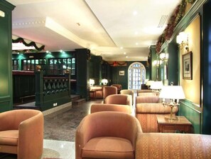 Un vestíbulo de hotel con zona de bar, asientos y un amplio ventanal en arco.