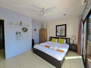 A bedroom with a bed, a ceiling fan, a mirror, and a window with curtains. - Lily holiday  (Patong)