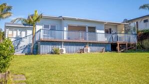 A two-story house with a blue balcony, a small front yard, and a satellite dish. - Snells Beach Family Retreat — Walk to Shops & Beach (Snells Beach)