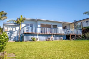 A two-story house with a blue balcony, a small front yard, and a satellite dish. - Snells Beach Family Retreat — Walk to Shops & Beach (Snells Beach)