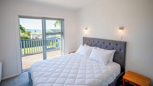 A bedroom with a large bed, a balcony, and a view of the outdoors. - Snells Beach Family Retreat — Walk to Shops & Beach (Snells Beach)