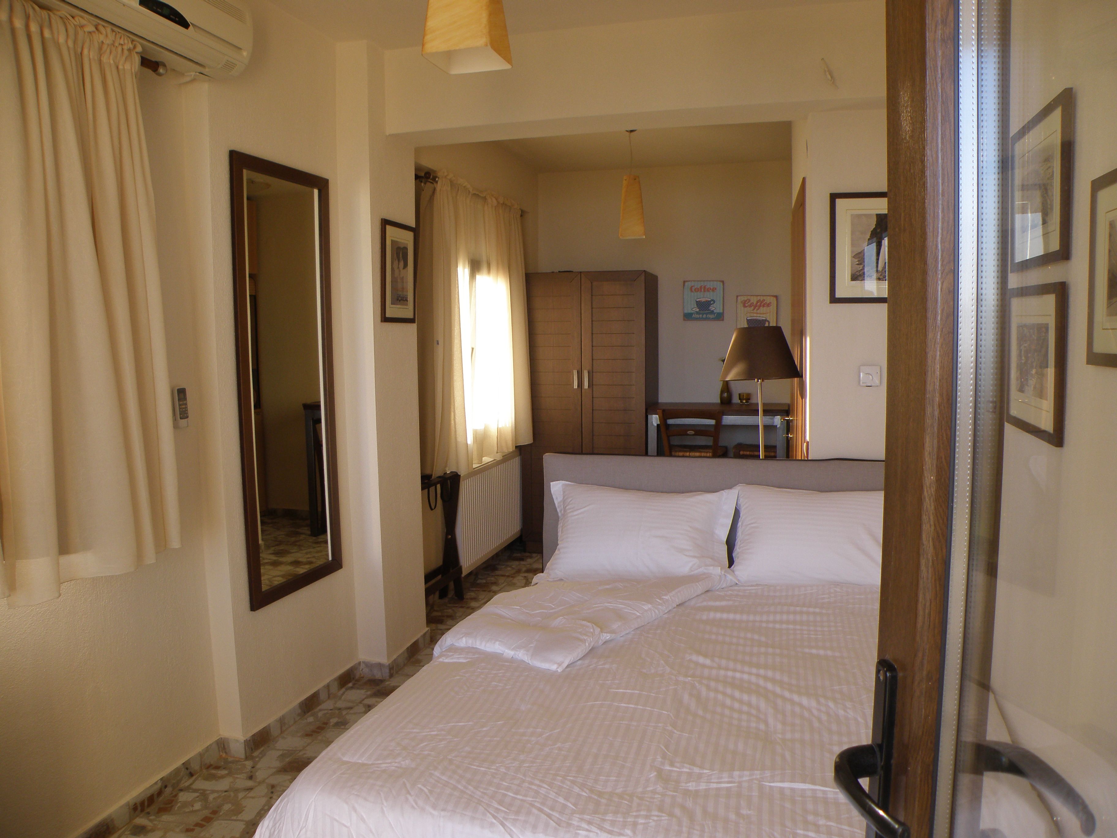 A hotel room with a bed, a desk, a chair, and a radiator.