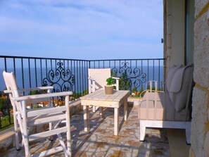 A balcony with a view of the sea, furnished with white chairs and a table, and a potted plant. - Palamidi Boutique Apartments (Kassandra)