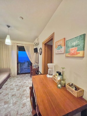 Una habitación acogedora con una mesa de comedor de madera, una cafetera y vistas al balcón.