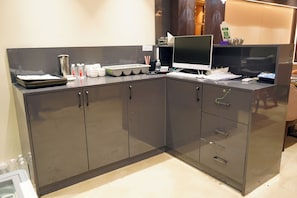 A modern kitchen with grey cabinets, a stainless steel sink, and a flat-screen TV. - Shrigo Hotel Banaras - Varanasi (Varanasi)