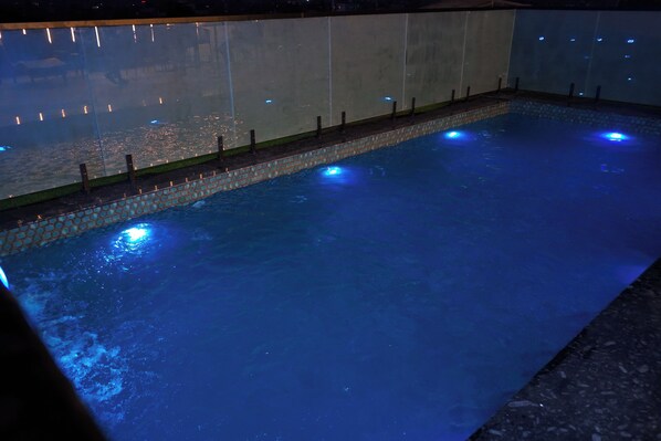 A swimming pool with a tiled edge and a glass wall. - Shrigo Hotel Banaras - Varanasi (Varanasi)