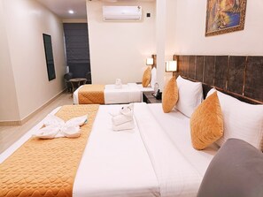 A hotel room with two beds, a dark headboard, and a painting on the wall. - Shrigo Hotel Banaras - Varanasi (Varanasi)
