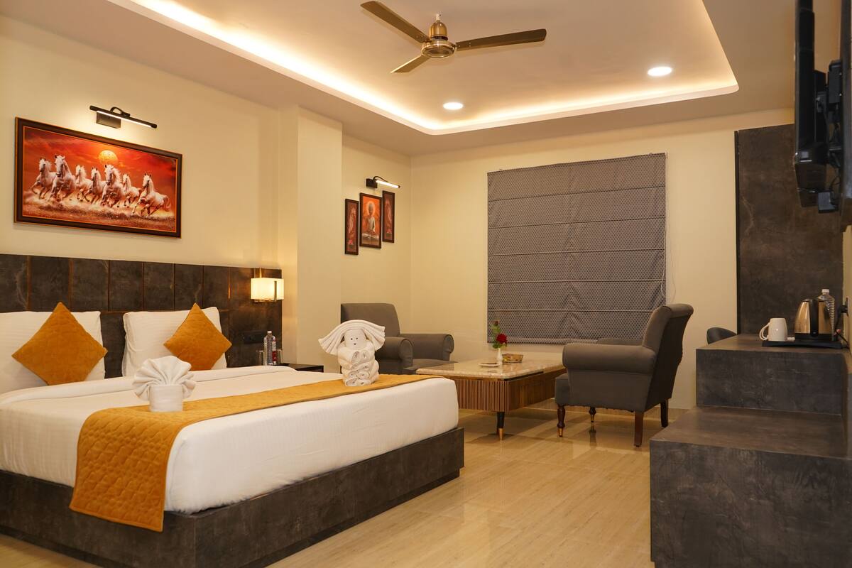 A hotel room with a large bed, a desk, a chair, and a ceiling fan.