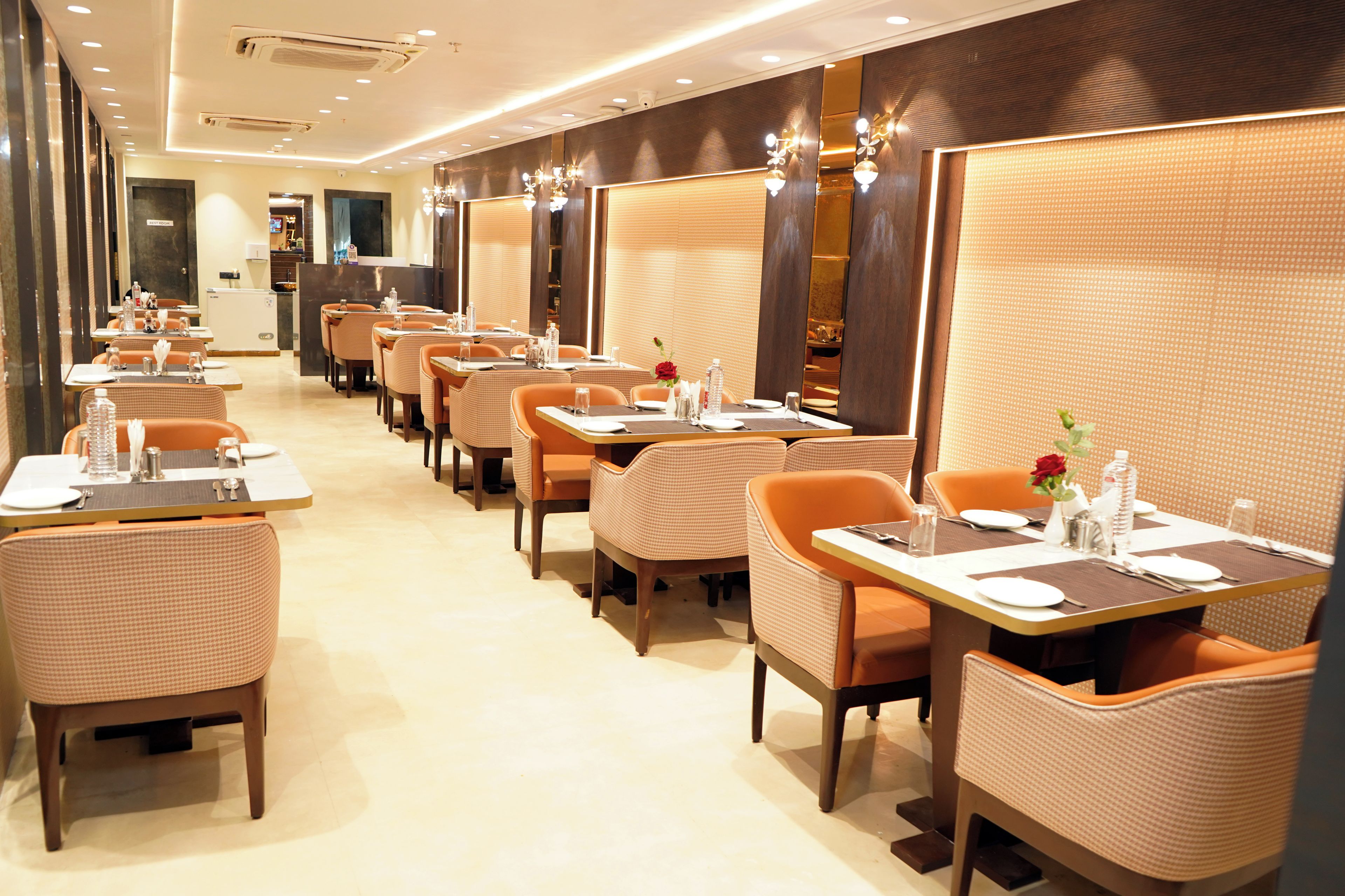 Un restaurant doté de nombreuses tables et de banquettes, chacune étant équipée de couverts et de chaises.