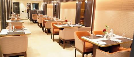 Un restaurant doté de nombreuses tables et de banquettes, chacune étant équipée de couverts et de chaises.