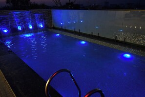 Una piscina con iluminación azul y una pared de vidrio.