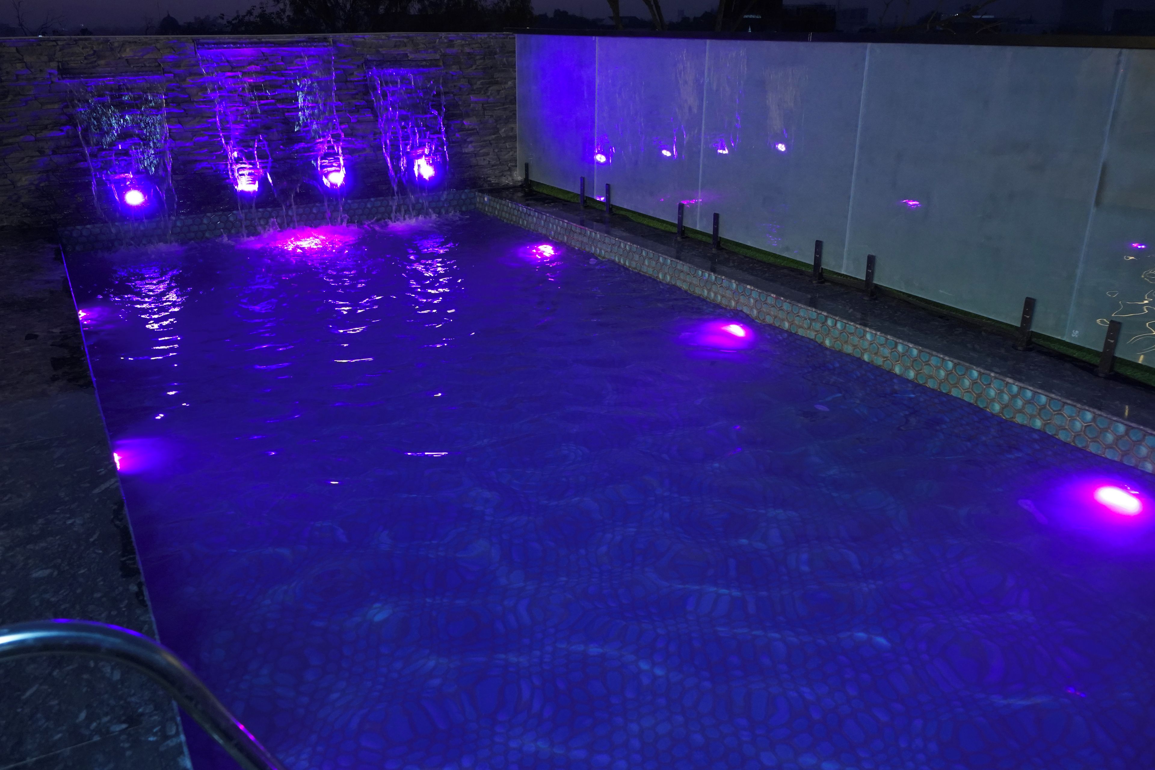 Une piscine agrémentée de jeux d’eau et bordée d’un mur en pierre.