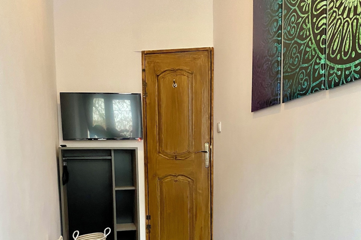 Een kamer met een bed, een televisie op een plank, een houten deur en een wand met een decoratief patroon.