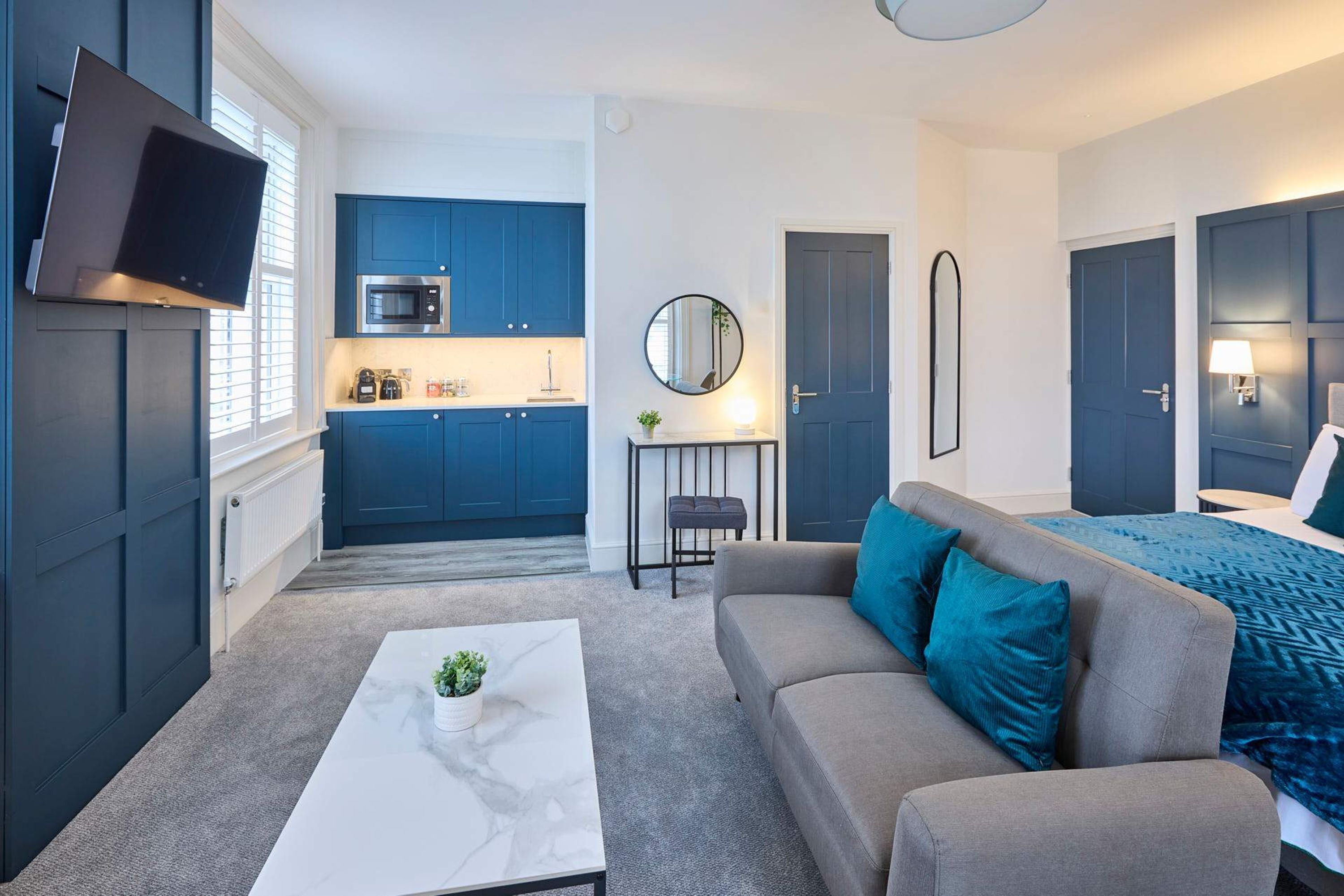 A compact living space with a kitchenette, a sofa, a coffee table, and a bed.