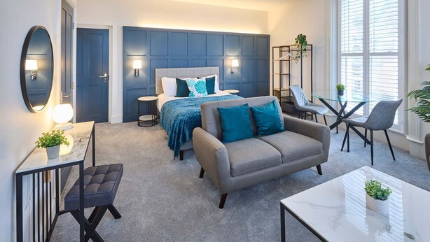Et moderne hotelværelse med seng, sofa og spiseplads.