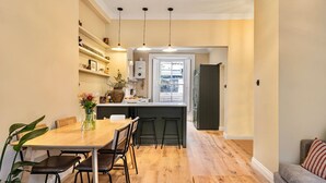 A modern kitchen with a wooden dining table, bar stools, and pendant lighting. - Notting Hill 4-bed Private Garden Home Office (London)